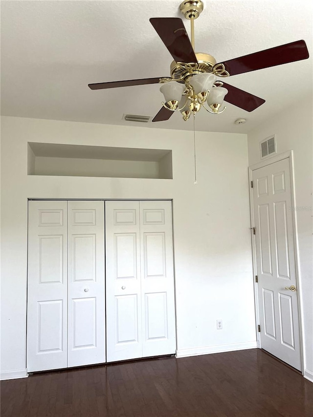 unfurnished bedroom with ceiling fan, a closet, and dark hardwood / wood-style floors