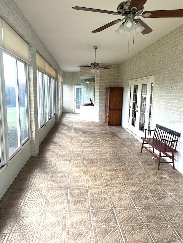 unfurnished sunroom with a healthy amount of sunlight, ceiling fan, and french doors