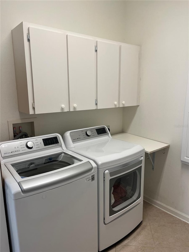 washroom with cabinets, washing machine and clothes dryer, and light tile patterned flooring