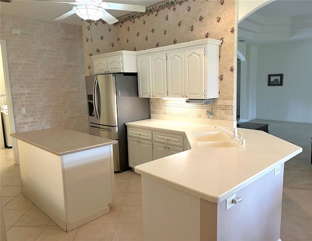 kitchen featuring ceiling fan, sink, kitchen peninsula, white cabinetry, and stainless steel refrigerator with ice dispenser