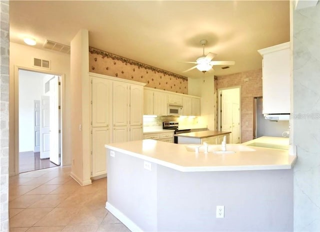 kitchen featuring white cabinets, kitchen peninsula, light tile patterned floors, ceiling fan, and stainless steel range with electric cooktop