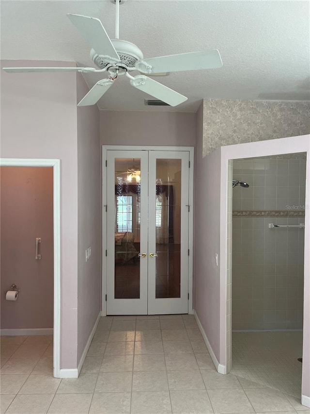 unfurnished bedroom with a textured ceiling, light tile patterned floors, ceiling fan, and french doors