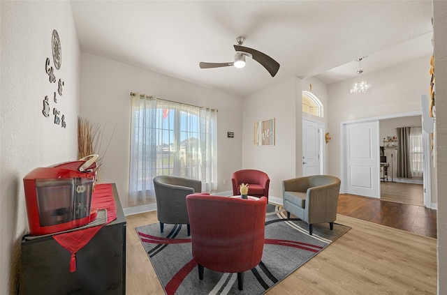 living room with ceiling fan with notable chandelier and hardwood / wood-style flooring