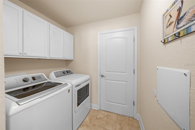 clothes washing area featuring cabinets, light tile patterned floors, and washer and dryer