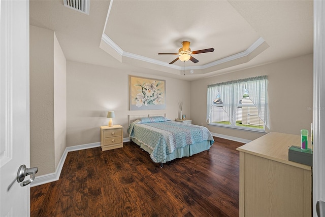 bedroom with ceiling fan, ornamental molding, a tray ceiling, and dark wood-type flooring