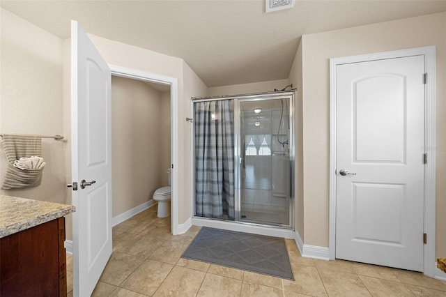 bathroom with tile patterned flooring, a shower with door, vanity, and toilet