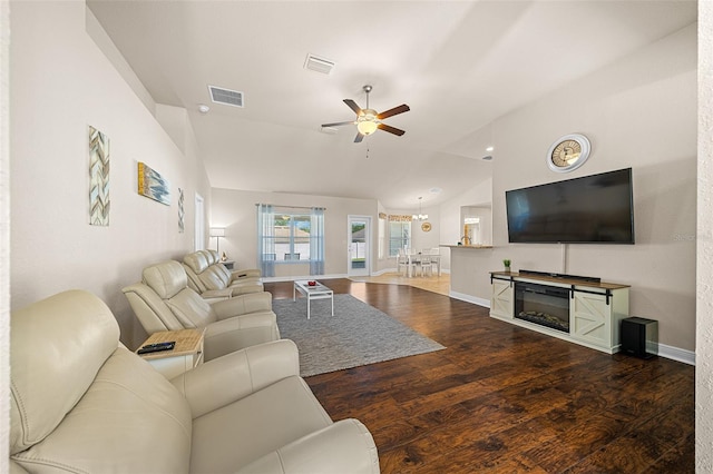 living room with ceiling fan with notable chandelier, vaulted ceiling, and dark wood-type flooring