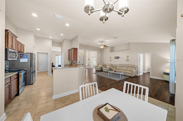 dining room with ceiling fan with notable chandelier, lofted ceiling, and light hardwood / wood-style floors