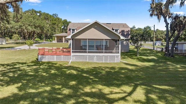 rear view of property with a deck, a sunroom, and a yard