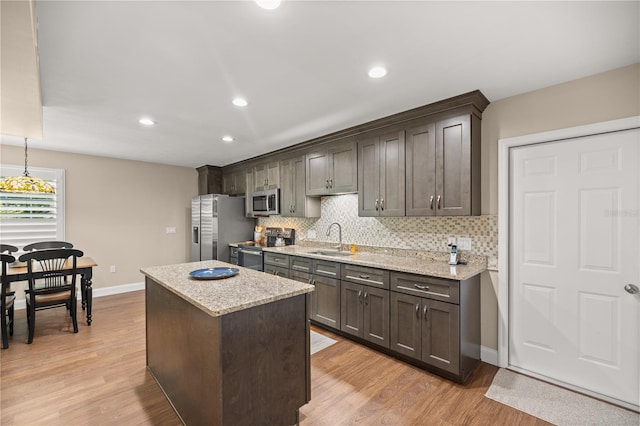 kitchen featuring light wood-type flooring, appliances with stainless steel finishes, dark brown cabinetry, and sink