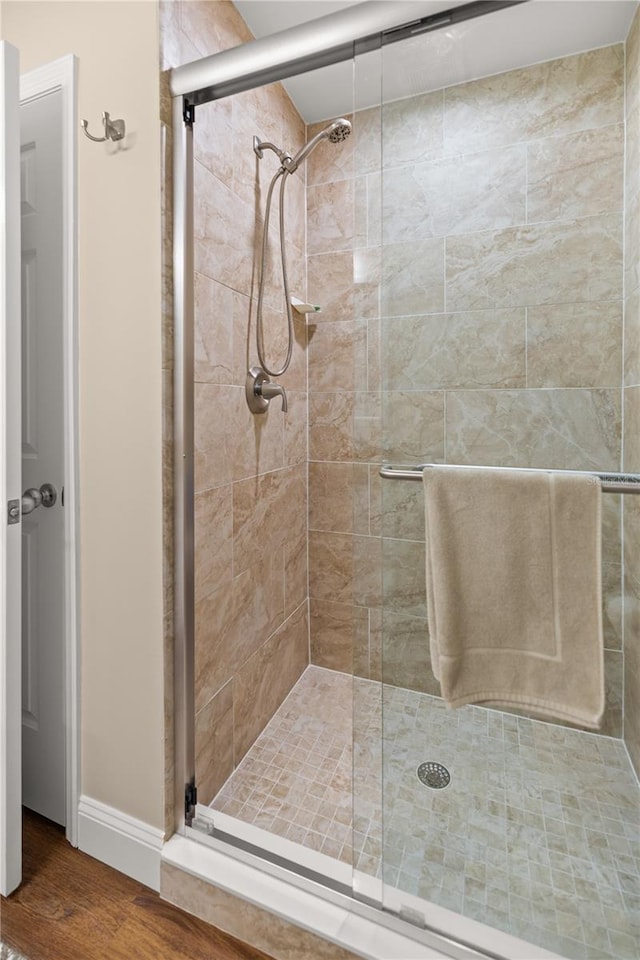 bathroom with a shower with door and hardwood / wood-style floors