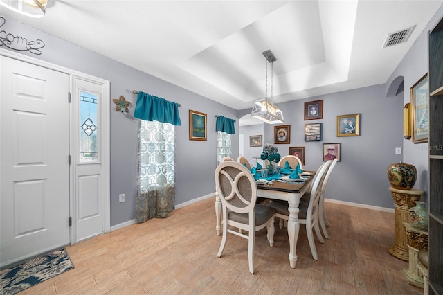 dining space featuring light hardwood / wood-style flooring and a raised ceiling