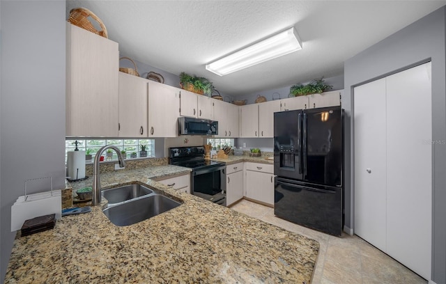 kitchen featuring a textured ceiling, sink, kitchen peninsula, black appliances, and light stone countertops