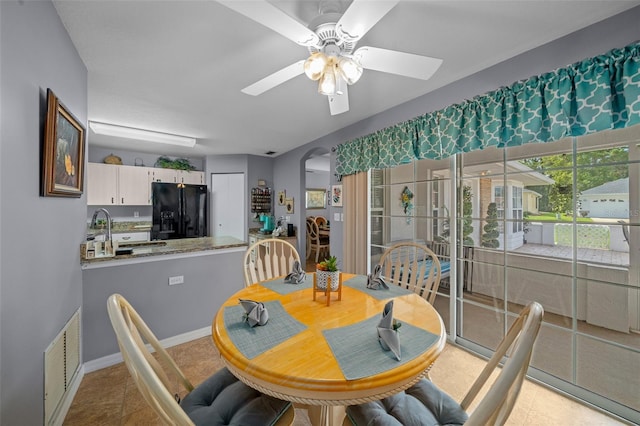 dining space featuring light tile patterned floors, sink, and ceiling fan