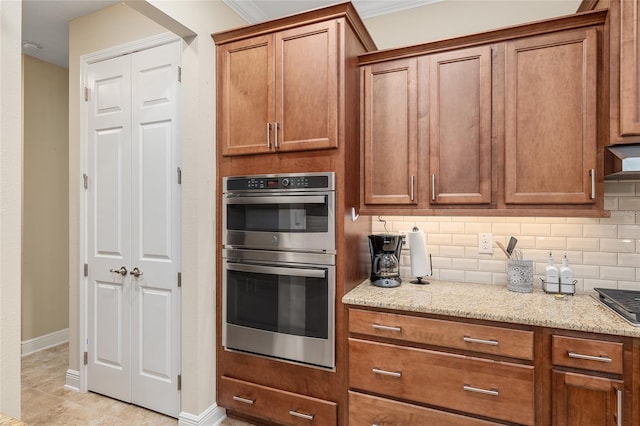 kitchen featuring light stone counters, light tile patterned flooring, backsplash, double oven, and crown molding