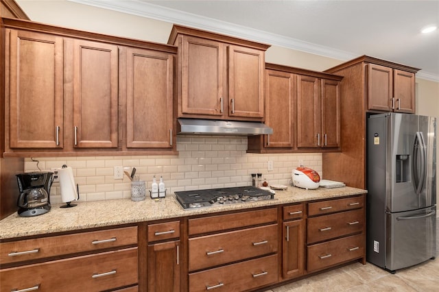 kitchen featuring light tile patterned floors, ornamental molding, appliances with stainless steel finishes, light stone countertops, and decorative backsplash