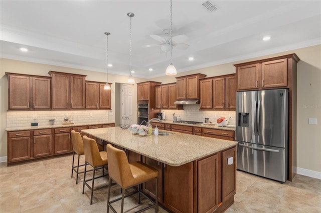 kitchen featuring an island with sink, sink, hanging light fixtures, appliances with stainless steel finishes, and a kitchen breakfast bar