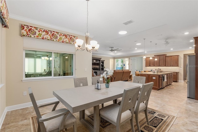 tiled dining area with ceiling fan with notable chandelier, crown molding, and sink