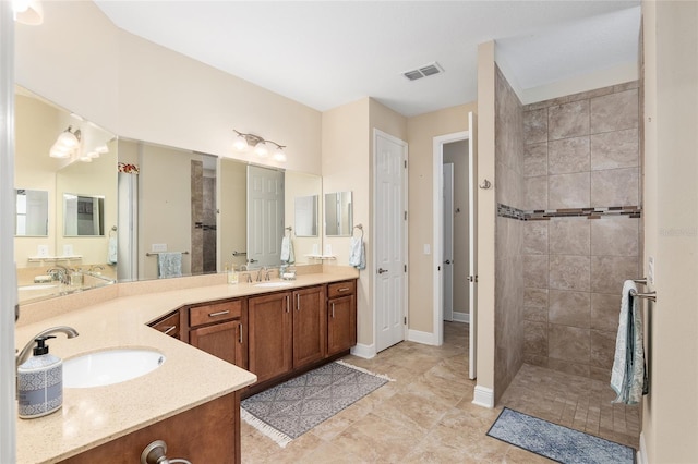 bathroom featuring tile patterned flooring, vanity, and tiled shower