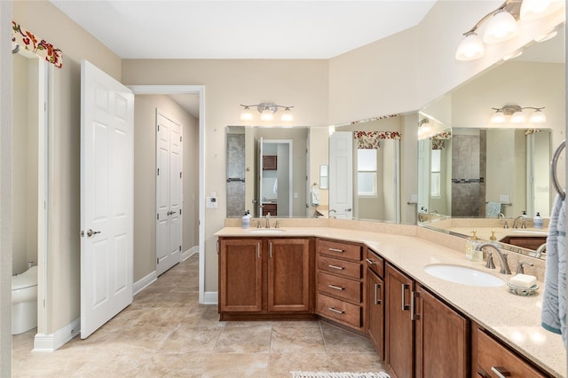 bathroom featuring toilet, tiled shower, and vanity