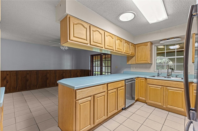 kitchen with dishwasher, sink, light tile patterned flooring, kitchen peninsula, and a textured ceiling