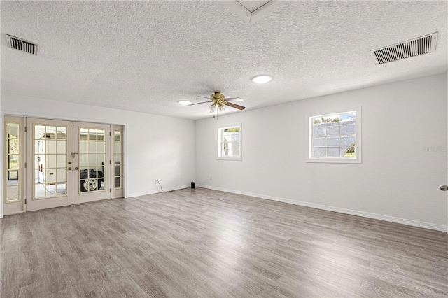 unfurnished room featuring ceiling fan, french doors, hardwood / wood-style flooring, and a textured ceiling