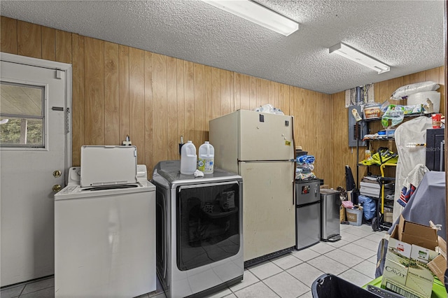 washroom with separate washer and dryer, wood walls, light tile patterned floors, and a textured ceiling