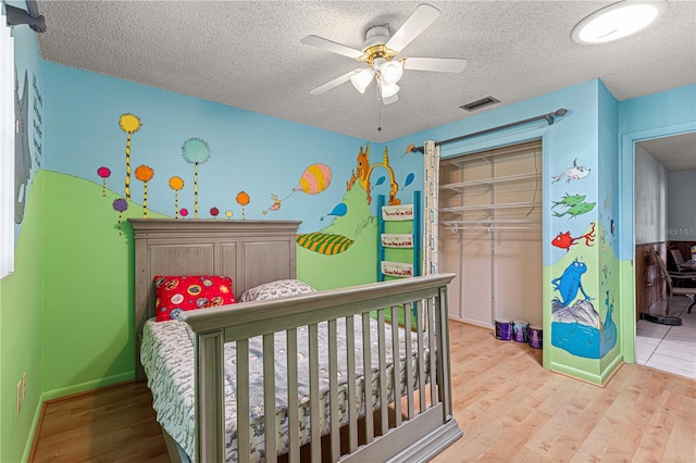 bedroom featuring ceiling fan, a textured ceiling, and light wood-type flooring