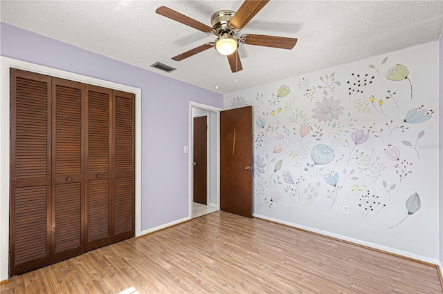 unfurnished bedroom with ceiling fan, a textured ceiling, a closet, and light hardwood / wood-style floors