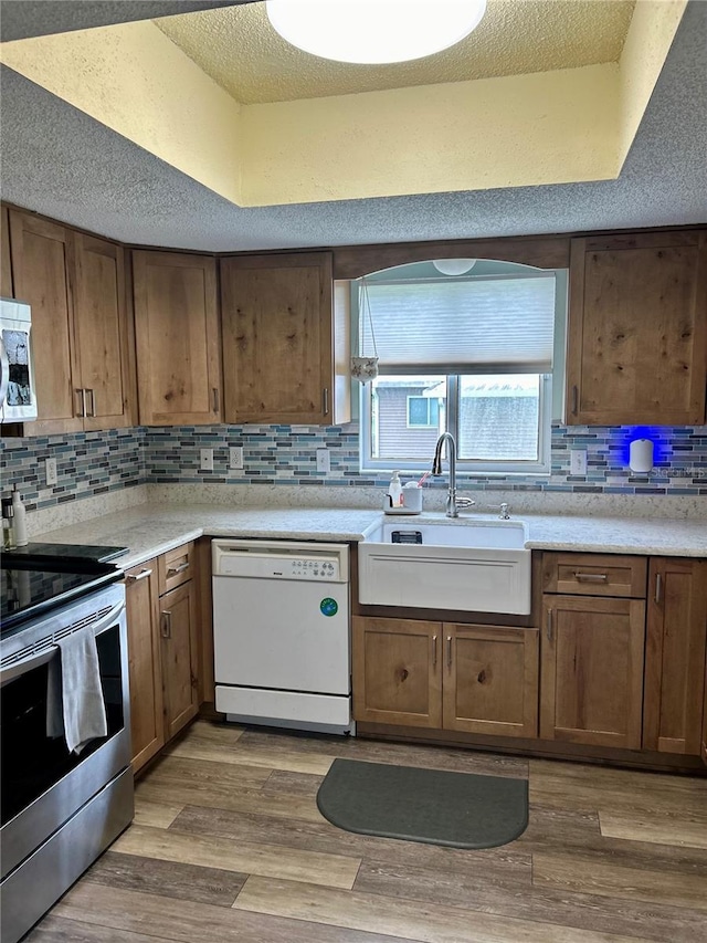 kitchen featuring sink, stainless steel appliances, light hardwood / wood-style floors, and decorative backsplash