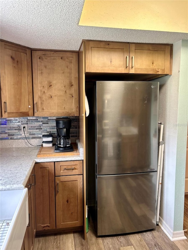 kitchen featuring decorative backsplash, light wood-type flooring, and stainless steel fridge