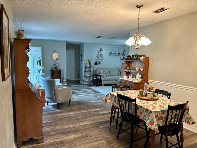 dining room featuring an inviting chandelier, a textured ceiling, and dark wood-type flooring