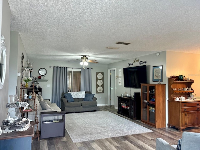 living room featuring a textured ceiling, wood-type flooring, and ceiling fan