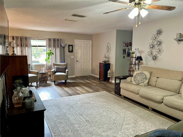 living room featuring ceiling fan, hardwood / wood-style flooring, and a textured ceiling