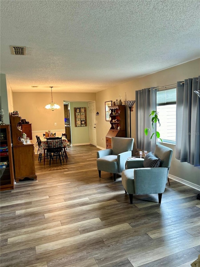 living room with a chandelier, a textured ceiling, and hardwood / wood-style flooring