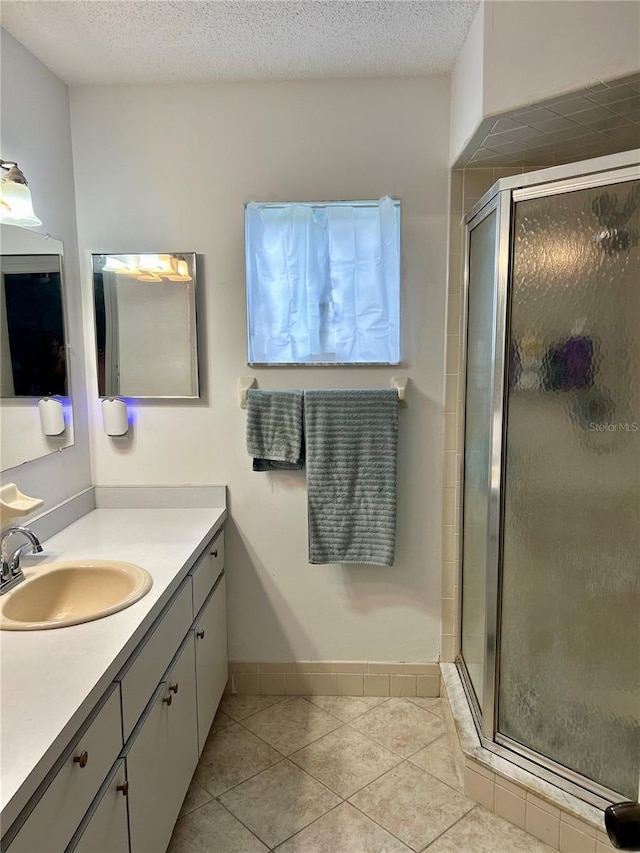 bathroom featuring walk in shower, a textured ceiling, vanity, and tile patterned floors