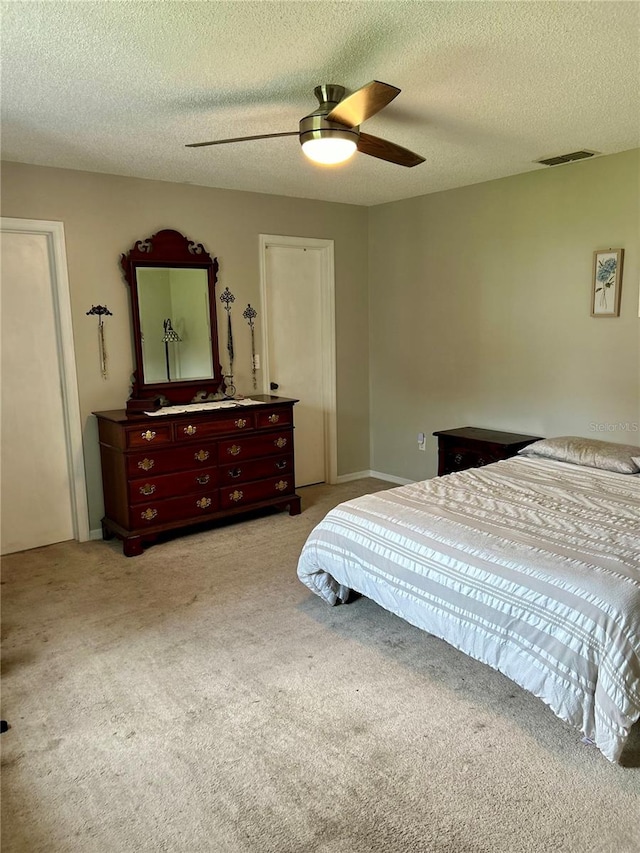 bedroom featuring ceiling fan, light colored carpet, and a textured ceiling