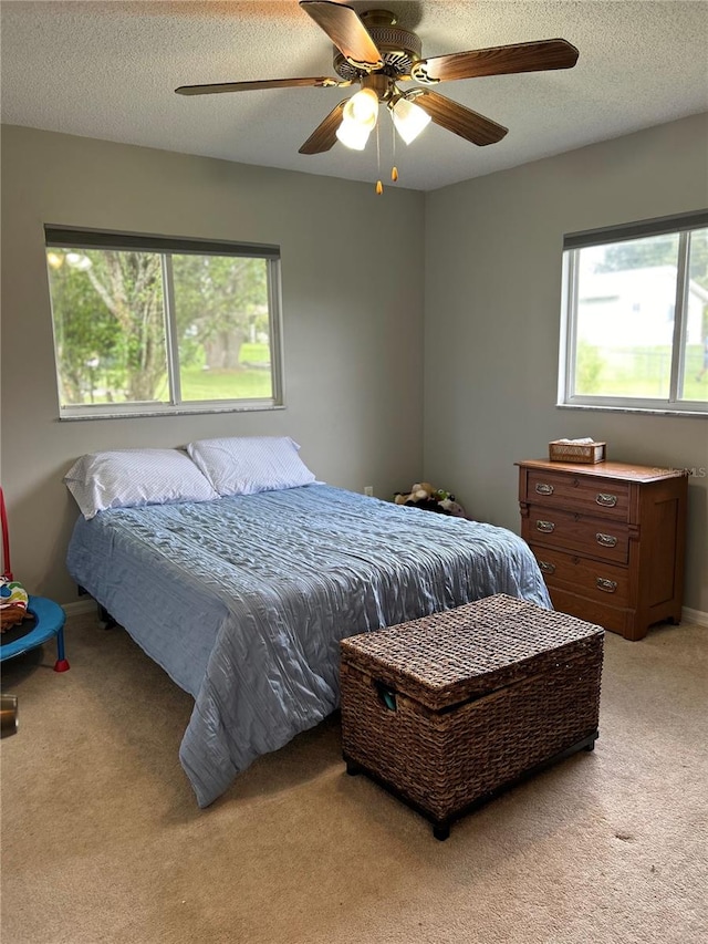 carpeted bedroom featuring ceiling fan and a textured ceiling