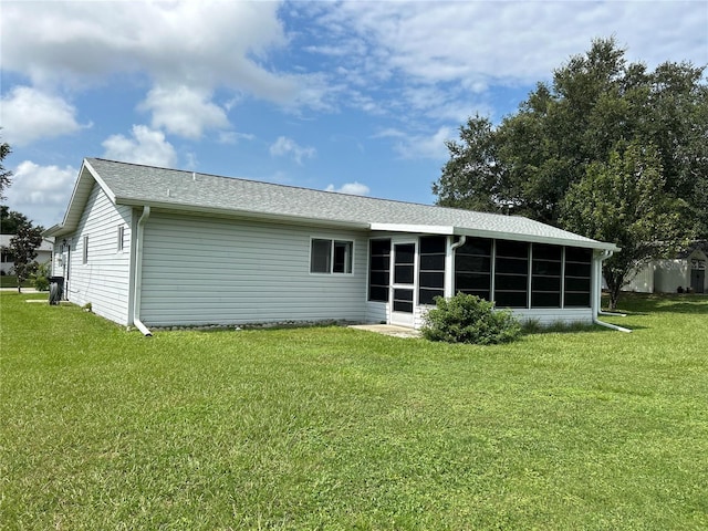 rear view of house featuring a sunroom and a yard