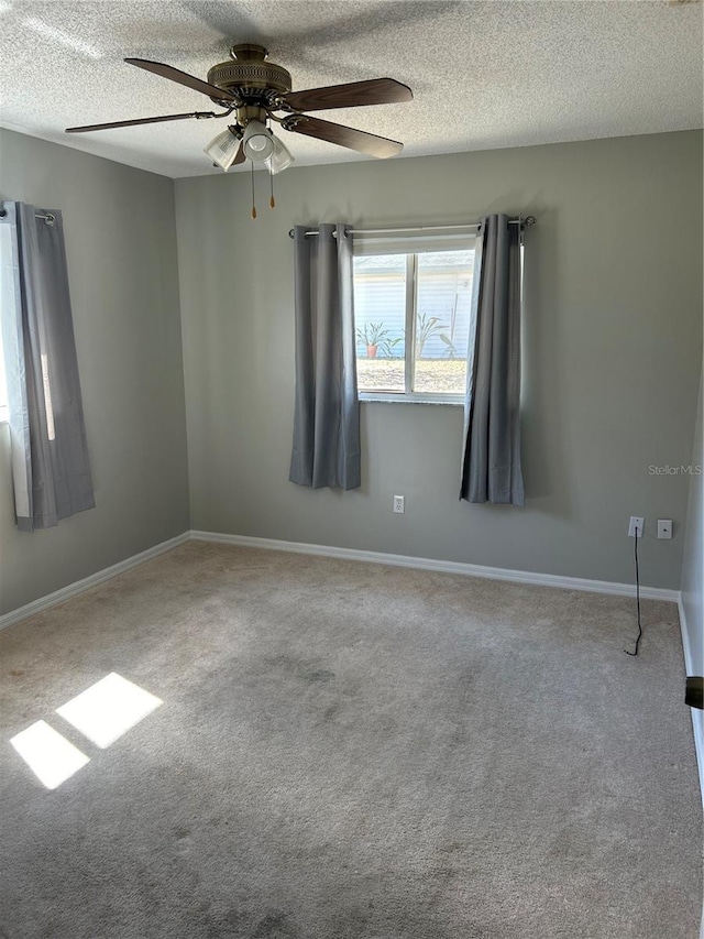 unfurnished room with carpet floors, ceiling fan, baseboards, and a textured ceiling