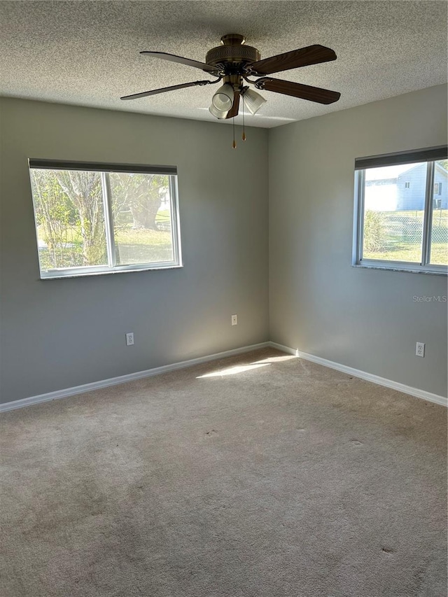 spare room with carpet floors, a ceiling fan, baseboards, and a textured ceiling