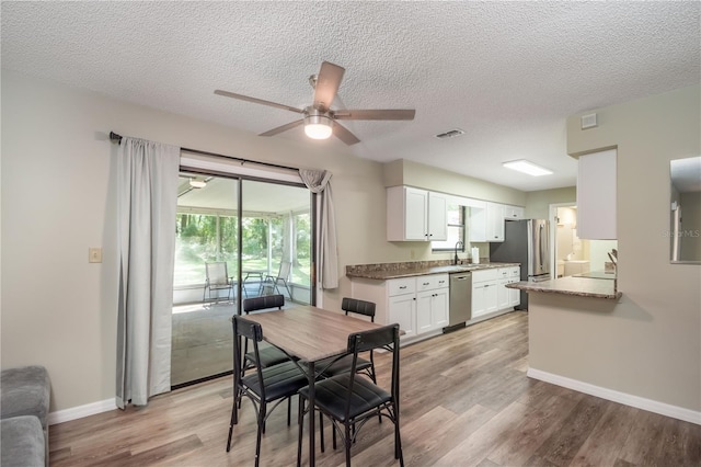 dining room featuring light wood-type flooring, a textured ceiling, sink, and ceiling fan