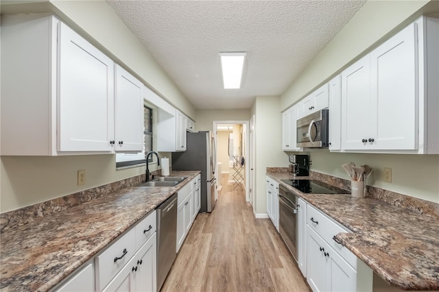 kitchen with light wood-type flooring, a textured ceiling, stainless steel appliances, and white cabinets