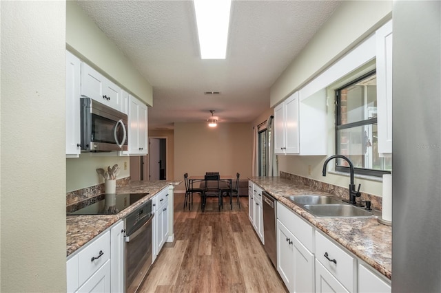 kitchen featuring sink, light hardwood / wood-style flooring, stainless steel appliances, and white cabinets