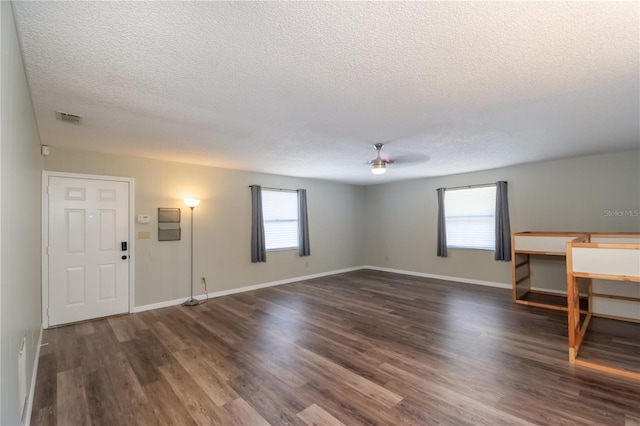 interior space with ceiling fan, dark wood-type flooring, and a healthy amount of sunlight