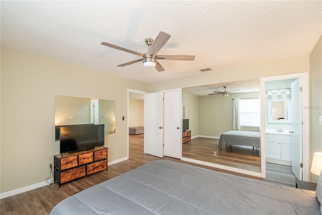 bedroom with ceiling fan, hardwood / wood-style flooring, ensuite bathroom, and a textured ceiling