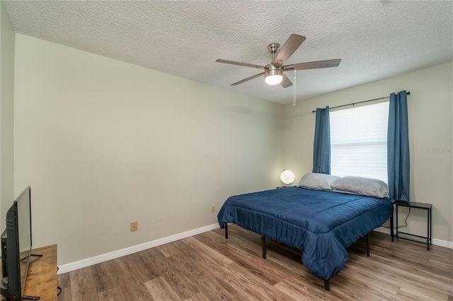 bedroom featuring light wood-type flooring, ceiling fan, and a textured ceiling