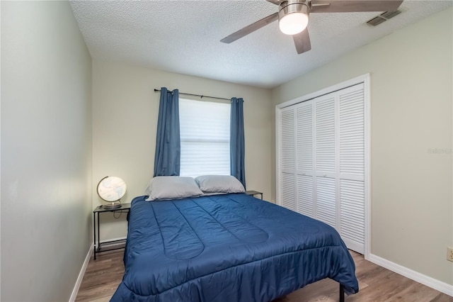 bedroom with a textured ceiling, hardwood / wood-style floors, ceiling fan, and a closet