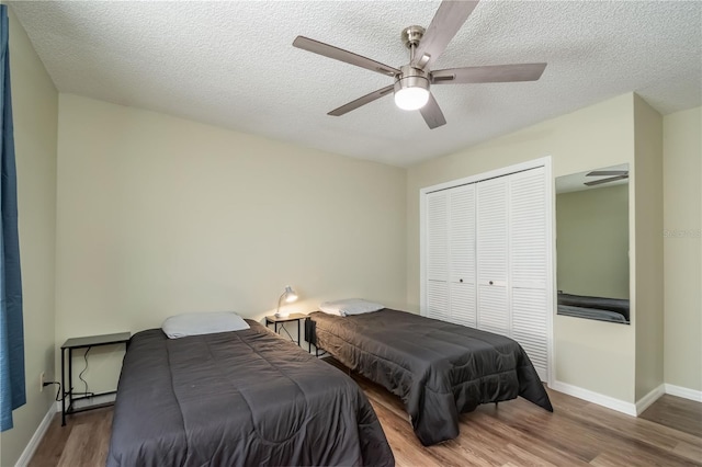 bedroom with a textured ceiling, ceiling fan, a closet, and hardwood / wood-style flooring