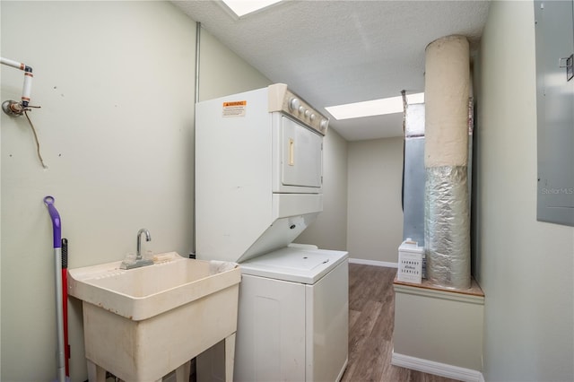 clothes washing area featuring wood-type flooring, stacked washer and clothes dryer, a textured ceiling, and sink